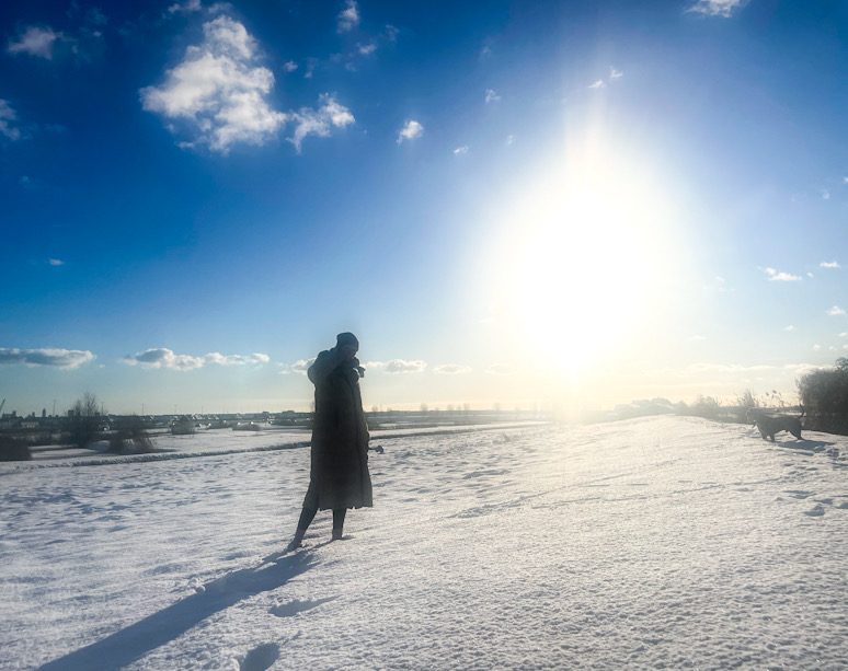 persoon loopt alleen in een open landschap met sneeuw en fel zonlicht